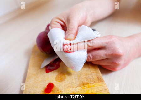 Una donna taglia stessa con un coltello da cucina Foto Stock