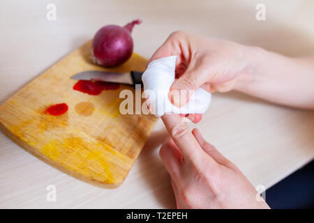 Una donna taglia stessa con un coltello da cucina Foto Stock