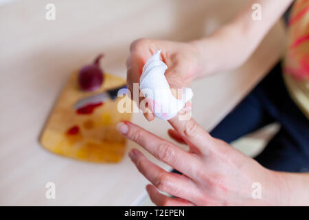 Una donna taglia stessa con un coltello da cucina Foto Stock