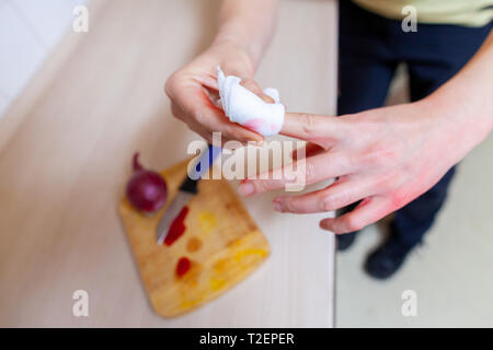 Una donna taglia stessa con un coltello da cucina Foto Stock