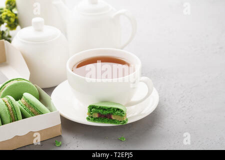Il pistacchio macarons con riempimento di frutti di bosco e tè per dessert. Chicche francese concetto. Foto Stock