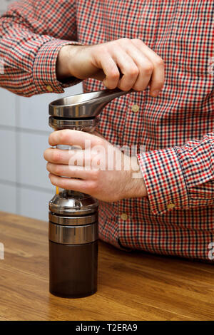 Le mani degli uomini fare il caffè. Barista braciole di caffè in un macinino da caffè. Foto Stock