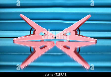 Due abiti rosa pioli posti contro uno sfondo blu. Foto Stock