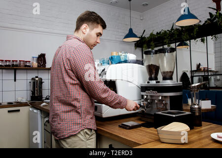 Bel giovane barista hipster fare il caffè per i suoi clienti nel cafe'. Foto Stock