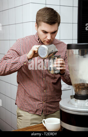 Bel giovane barista hipster fare il caffè per i suoi clienti nel cafe'. Foto Stock