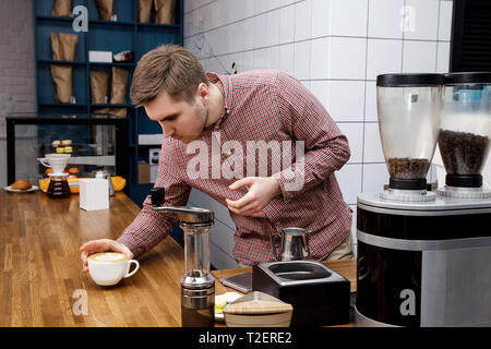 Bel giovane barista hipster fare il caffè per i suoi clienti nel cafe'. Foto Stock