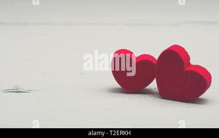 Due rosso cuore di legno forme su un turchese tavolo in legno con spazio per il testo Foto Stock