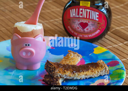 Uovo sodo in tazza di uova con soldati di toast e jar special edition giara di Valentine Marmite da Unilever - Concetto di colazione Foto Stock