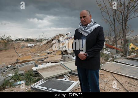 Suleiman al-Atika si trova tra le macerie della sua casa demolita rasa dalle autorità israeliane alla periferia di Rahat, una città prevalentemente beduina nel distretto meridionale di Israele del deserto di Negev. Molti beduini nel Negev vivono in comunità che sono state stabilite senza alcun permesso del governo, nel qual caso qualsiasi costruzione sul sito è considerata illegale. Lo stato emette ordini di demolizione contro la costruzione costruita senza un permesso, ma non tutto è in villaggi non riconosciuti. Alcuni si trovano in comunità beduine legalmente riconosciute. Foto Stock