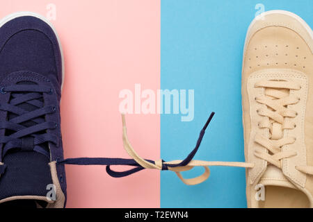 Sneakers differenti. Lacci legati nel nodo sul clored rosa e blu. Coppia inscindibile o allegato in rapporti intimi concept Foto Stock