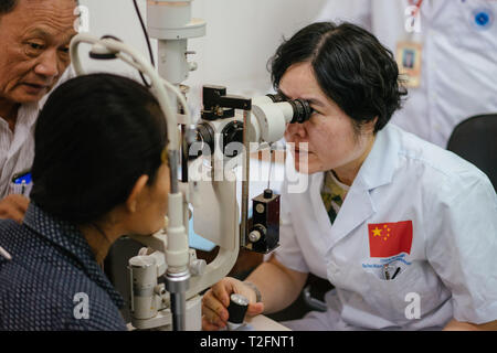 (190402) -- Phnom Penh, 2 aprile 2019 (Xinhua) -- Medico Liang Hao (R) del primo ospedale affiliato del Guangxi Medical University conduce pre-operative check-up per somma Meyle davanti a una operazione di cataratta a Kampong Cham ospedale provinciale in Kampong Cham, Cambogia, Marzo 15, 2019. Somma Meyle, 36 è una madre single con cinque bambini. Per contribuire a migliorare le loro condizioni finanziarie, due di Meyle le figlie sono ora al lavoro nella capitale Phnom Penh mentre due dei suoi figli vivono in bambini casa di cura. Meyle ora vive in una baraccopoli in affitto casa con la sua figlia più giovane. Meyle aveva Foto Stock