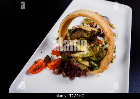 Vino set costituito da carne affumicata, salsicce, formaggio, uva, cherry-pomodori, olive, foglie di basilico e foglie di rucola e pomodori secchi su di un legno rustico board Foto Stock