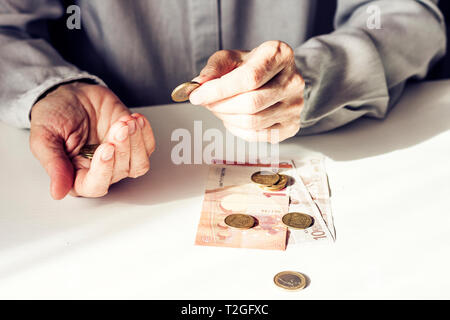 Euro e monete in vecchia donna le mani su sfondo bianco con spazio di copia Foto Stock