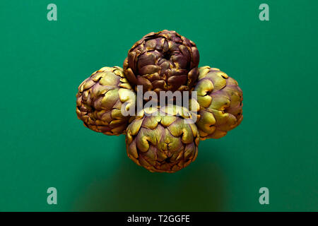Gruppo di 4 carciofi isolato dal di sopra al di sopra di un verde oliva flatlay sfondo concept Foto Stock