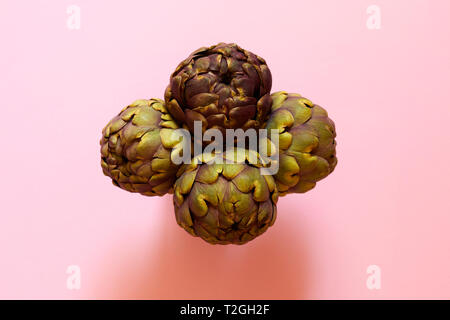 Gruppo di 4 carciofi isolato dal di sopra su un sfondo rosa flatlay concept Foto Stock