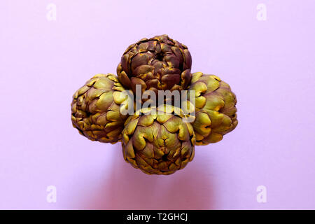Gruppo di 4 carciofi isolato dal di sopra su un sfondo viola flatlay concept Foto Stock
