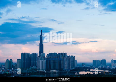 Edificio alto e moderno di edifici e gru Siagon accanto al fiume al tramonto. La città di Ho Chi Minh (Saigon), il Vietnam Asia Foto Stock