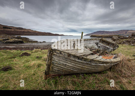 Un vecchio, abbandonati e stagionato in barca da pesca che giace in qualche erba nei pressi di una baia sul Isle of Mull, Ebridi, Scotland, Regno Unito Foto Stock