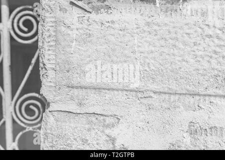 Un close-up di un frammento di una vecchia porta rurale. Recinzione in pietra e la porta di metallo con ornamenti. Profondità di messa a fuoco, texture, sfondo. In bianco e nero Foto Stock