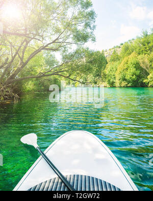 White stand up paddle board senza persona galleggiando giù bel fiume con turchesi acque cristalline su soleggiate giornate estive, Zrmanja, Dalmazia, Croazia Foto Stock