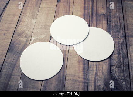 Tre blank white beer coasters su sfondo di legno. Design sensibile mockup. Foto Stock