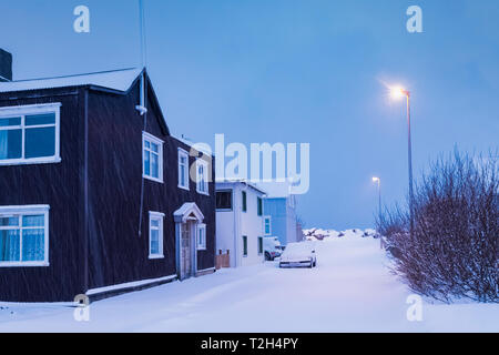 Coperte di neve street nelle prime ore del mattino nel villaggio di Flateyri lungo Önundarfjörður (fjord) nel Westfjords dell Islanda [alcuna proprietà di rilascio; Foto Stock