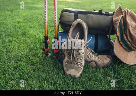 Pali trekking, stivali, , il sacco a pelo , hat e altre apparecchiature backpacker, sull'erba verde close-up Foto Stock