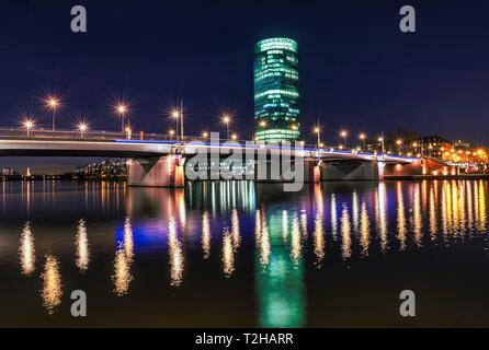 Vista di Friedensbrucke con Westhafen Tower, la riflessione delle luci del principale, Schaumainkai, Frankfurt am Main, Hesse, Germania Foto Stock