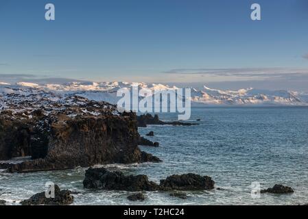 Costa di lava, coperta di neve paesaggio montano sul retro, Hellnar, Snaefellsnes peninsula, Vesturland, Islanda Foto Stock