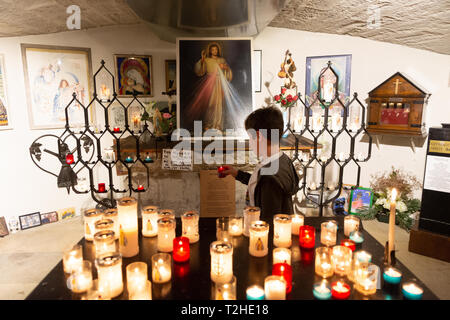 Les Saintes-Maries-de-la-Mer: candele e ragazzo che porta una candela recanti l'effigie di San Sarah, patrono del popolo rom, nella cripta della Foto Stock