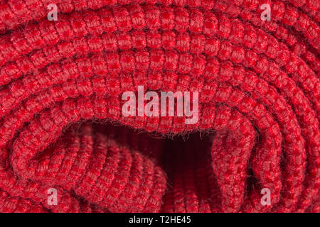Close-up / macro estreme di orange materiale in poliestere con red cucitura. Metafora arrotolato su un rullo, tessuto bordo. Foto Stock