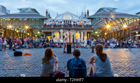 Guardare la folla degli artisti di strada a Covent Garden di Londra, Inghilterra, Regno Unito, Europa Foto Stock