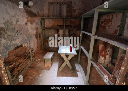 Stato orientale penitenziario - Cella con ripiani in legno, tavolo e sgabello in un abbandonato cella di prigione Foto Stock