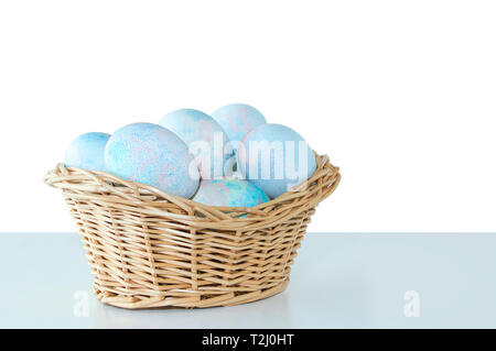 Giallo di Pasqua le uova in un cesto di paglia. Sul tavolo. Isolare in bianco sullo sfondo bianco Foto Stock