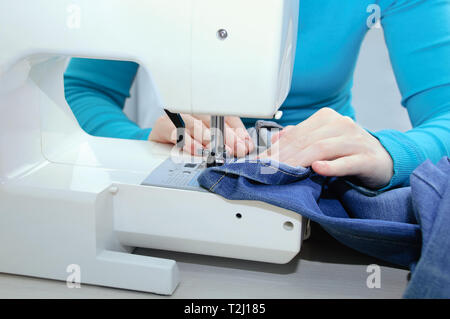 Ragazza caucasica denim cuce sulla macchina da cucire. Close-up. Foto Stock