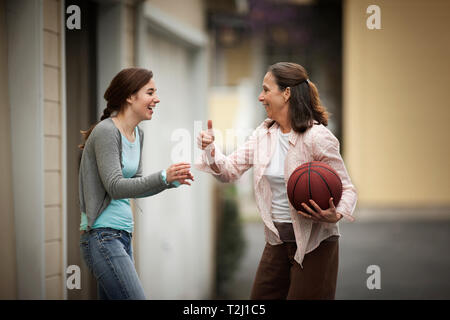 Felice madre e figlia giocare a basket sulla loro vialetto. Foto Stock