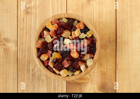 Mix di uva passa nera jumbo, mirtilli, piccola frutta candita pezzi di papaia, Mango, ananas in bambù ciotola sul tavolo di legno. Primo piano. Foto Stock