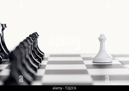 Messa a fuoco selettiva della scacchiera nera con pezzi di scacchi e pedone bianco davanti isolato su bianco Foto Stock