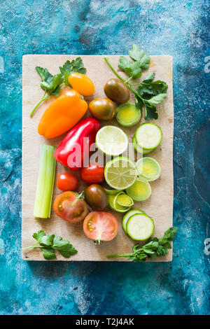 Cibo sano sfondo, lime tagliato a metà, sedano, peperoni, piccoli pomodori colorati su un cutboard,vista dall'alto. Foto Stock