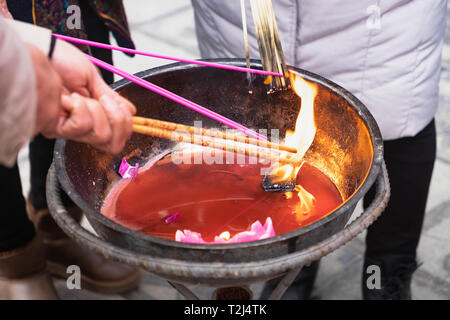 Close up di un altare con dragon carving, incenso bruciatore, joss pot, bastoncini di incenso bruciare con i fumi in un tempio buddista Foto Stock
