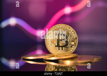 Golden bitcoin sono impilati su uno sfondo luminoso di grafici aziendali close-up. Bitcoin cryptocurrency Foto Stock