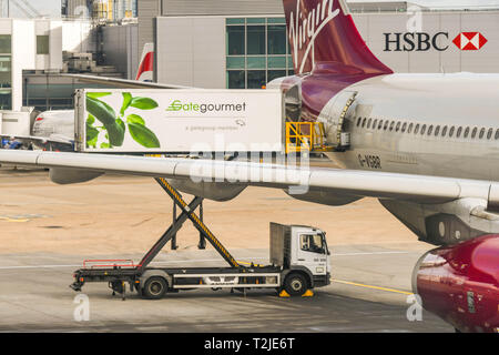 Dall'Aeroporto Heathrow di Londra, Inghilterra - Febbraio 2019: un Gate Gourmet elevatore a pantografo del carico del veicolo catering attraverso lo sportello posteriore di un Virgin Atlantic jet Foto Stock