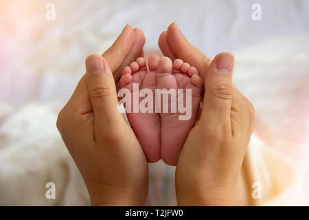 Madre Mani piccoli piedi del bambino. Close-up minuscoli piedi del bambino in mani. Madre cura del neonato. Una piccola Kid dita. Foto Stock