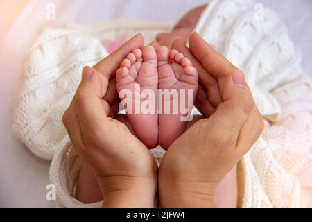 Madre Mani piccoli piedi del bambino. Close-up minuscoli piedi del bambino in mani. Madre cura del neonato. Una piccola Kid dita. Foto Stock