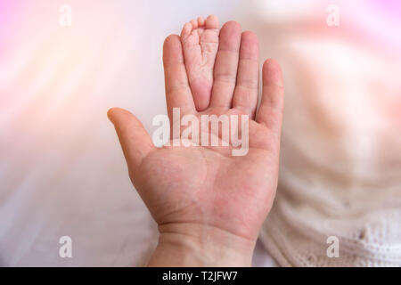 Padre Mani piccoli piedi del bambino. Close-up minuscoli piedi del bambino in mani. Padre cura del neonato. Una piccola Kid dita. Foto Stock