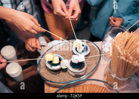 Strung marshmallows su un incendio di piccole dimensioni su un tavolo a una festa di nozze. Foto Stock