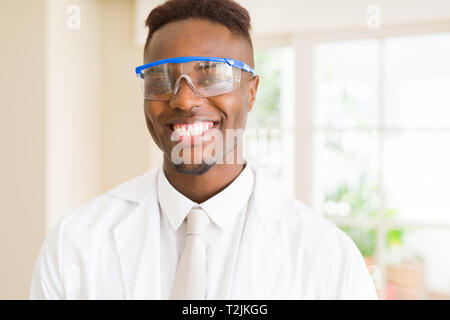 Africa scienziato giovane uomo che indossa gli occhiali di sicurezza lavorando con apparecchiature chimiche sorridente fiducioso Foto Stock