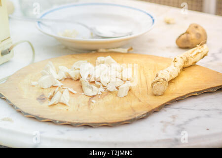 Radice di rafano tagliato a fette sulla scheda. Tabella con una piastra. Foto Stock