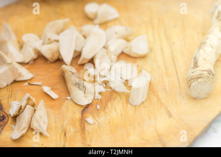 Radice di rafano tagliato a fette sulla scheda. Vista dall'alto. Foto Stock