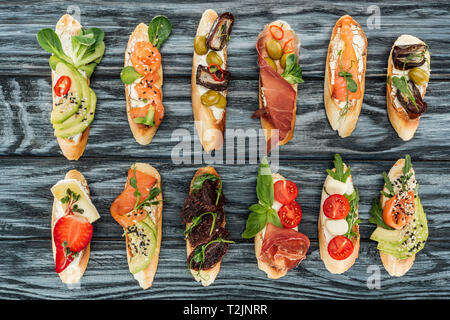 Vista superiore della lingua italiana bruschetta con prosciutto, il salmone e le verdure su una superficie di legno Foto Stock